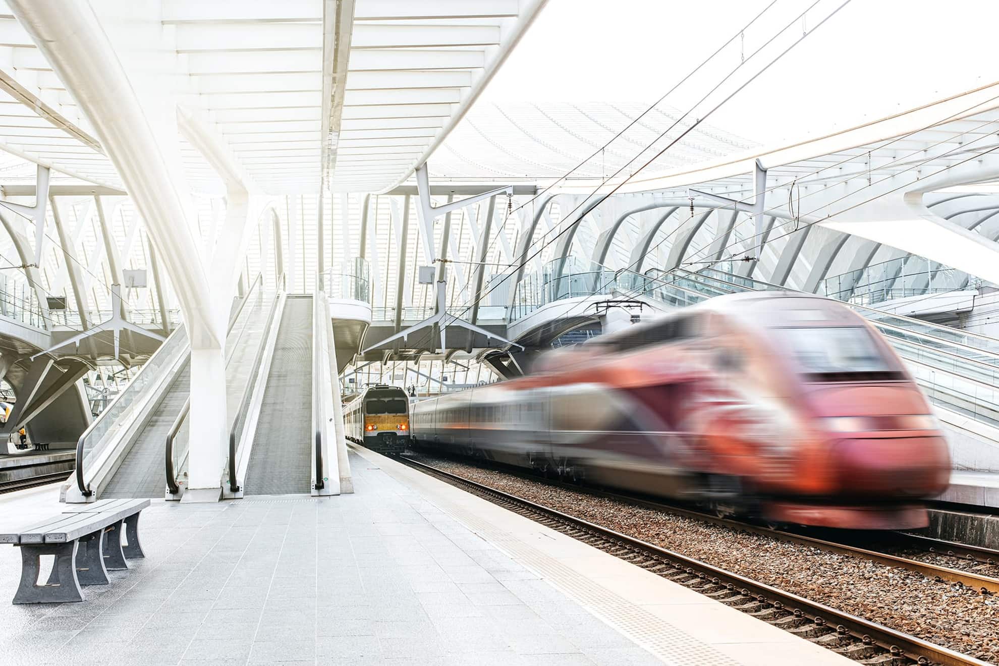 Schnell vorbeifahrender roter Zug im weißen futuristischen Bahnhof