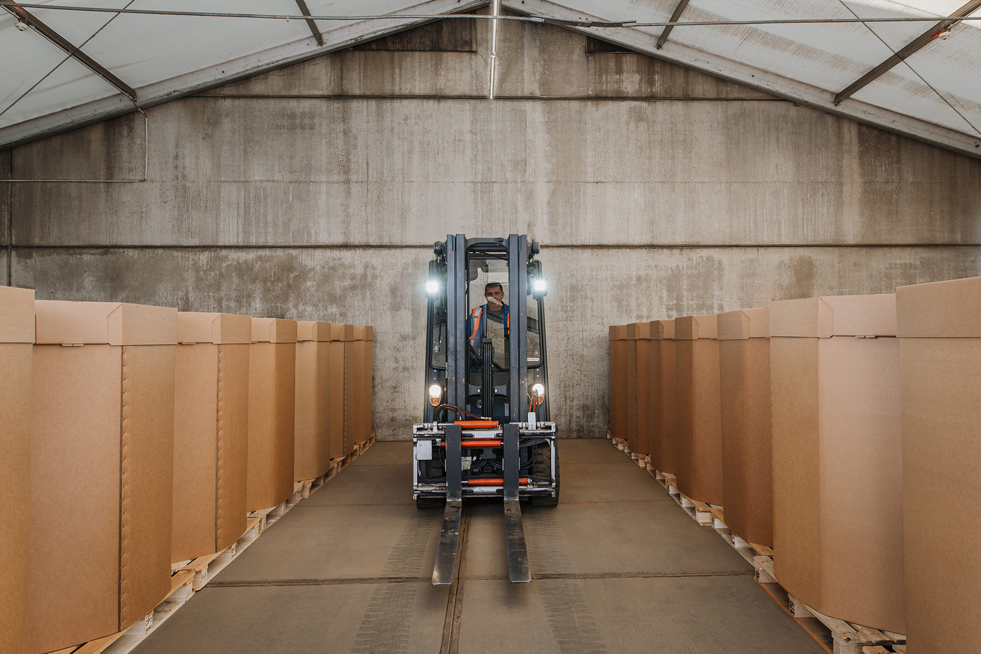 Industriefotografie eines Stapelfahrers umgeben von großen Kartons